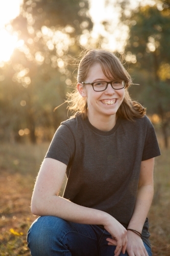 Portrait of a happy teenage girl with glasses smiling at the camera - Australian Stock Image