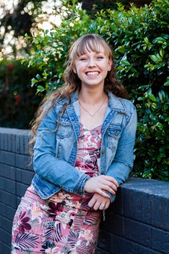 Portrait of a happy young woman leaning on a wall