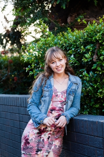 Portrait of a happy young woman leaning on a wall - Australian Stock Image