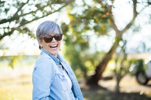 portrait of a senior woman in the garden wearing sunglasses - Australian Stock Image