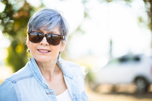 portrait of a senior woman in the garden wearing sunglasses - Australian Stock Image