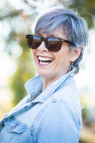 portrait of a senior woman in the garden wearing sunglasses - Australian Stock Image