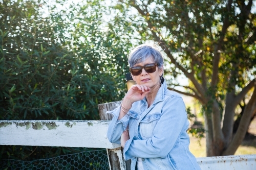 portrait of a senior woman in the garden wearing sunglasses - Australian Stock Image