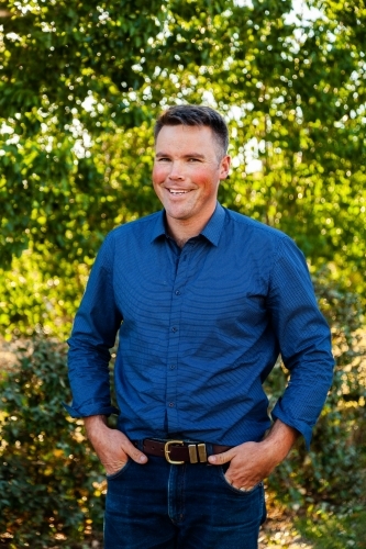 Portrait of a smiling man with bokeh green background - Australian Stock Image