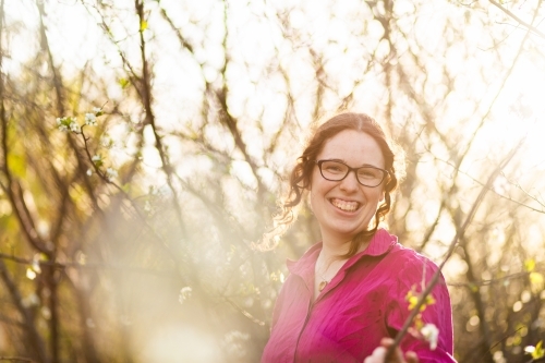 Portrait of a smiling young woman surrounded by white spring blossoms - Australian Stock Image