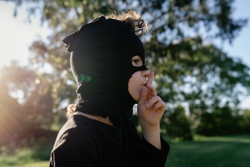 Portrait of a young boy dressed up as a Ninja, wearing a mask made from mum's stockings (pantyhose) - Australian Stock Image