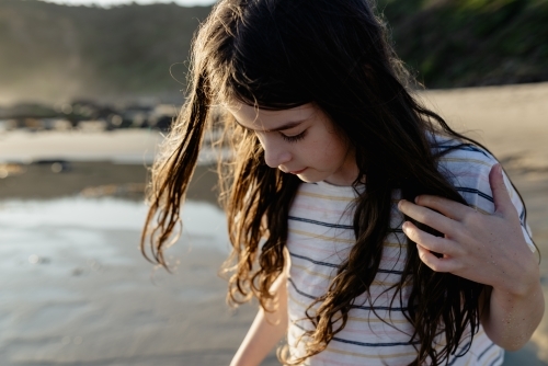 Portrait of a young girl with windswept hair on the beach at sunset - Australian Stock Image