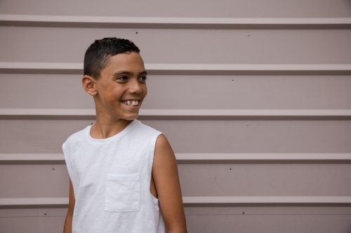 Portrait of a young, smiling first nations boy looking away from camera - Australian Stock Image