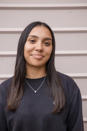 Portrait of a young, smiling,  first nations woman against wall outside - Australian Stock Image