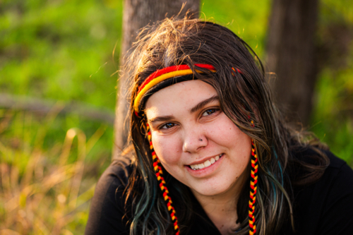 Portrait of Aboriginal Australian teenaged girl in golden light in bushland wearing headband - Australian Stock Image