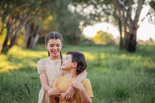 Portrait of bother and sister standing together in Australian country bush setting - Australian Stock Image