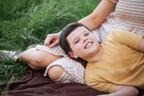 Portrait of boy lying on mother's lap in rural country bush setting - Australian Stock Image