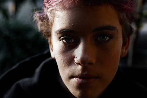 Portrait of depressed, angry teenage girl with short hair in dark, moody light - Australian Stock Image