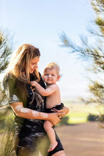 Portrait of first nations Australian mother with baby son by casuarina tree on cliff in country - Australian Stock Image