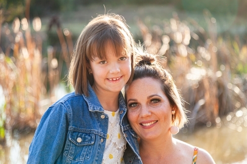 Portrait of happy mother in her thirties with daughter outside - Australian Stock Image