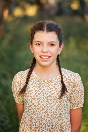 Portrait of happy pre-teen girl wearing dress in Australian country bush setting - Australian Stock Image