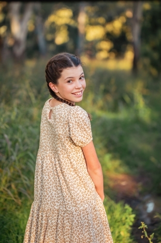 Portrait of happy pre-teen girl wearing dress in Australian country bush setting - Australian Stock Image