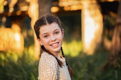 Portrait of happy pre-teen girl wearing dress in Australian country bush setting - Australian Stock Image