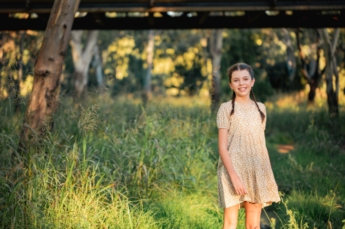 Portrait of happy pre-teen girl wearing dress in Australian country bush setting - Australian Stock Image