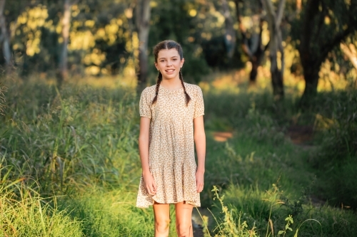 Portrait of happy pre-teen girl wearing dress in Australian country bush setting - Australian Stock Image