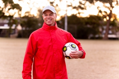 Portrait of male football coach wearing a cap and smiling proudly - Australian Stock Image