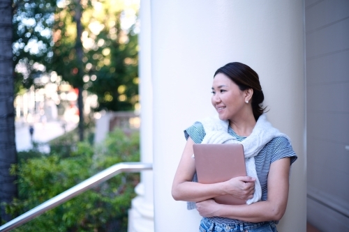Portrait of smiling woman holding laptop - Australian Stock Image