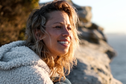 Portrait of smiling young woman on coastal clifftop at sunrise - Australian Stock Image