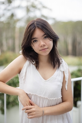 Portrait of teenage girl wearing white dress outside - Australian Stock Image