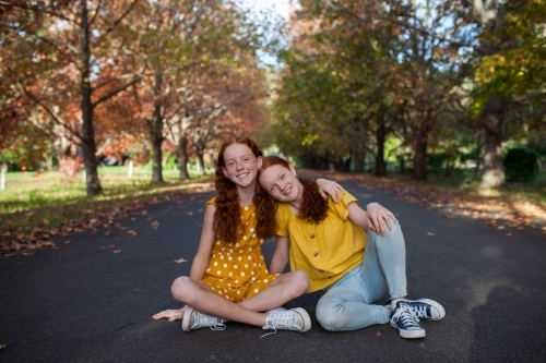 Portrait of two girls in a street lined with Autumn trees - Australian Stock Image