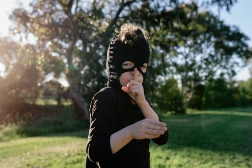 Portrait of young boy dressed up in Ninja costume, wearing a mask made from mum's pantyhose - Australian Stock Image