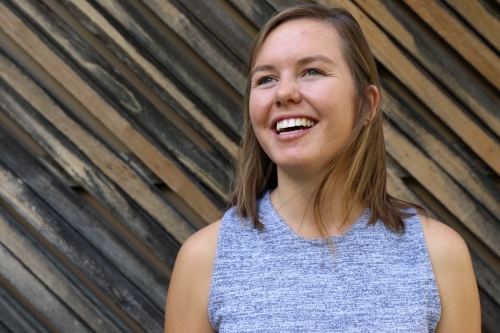 Portrait of young female outdoors with textured wooden background - Australian Stock Image