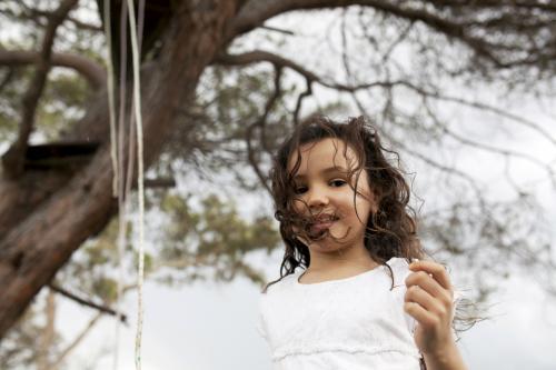 Portrait of young girl playing outside under a tree - Australian Stock Image