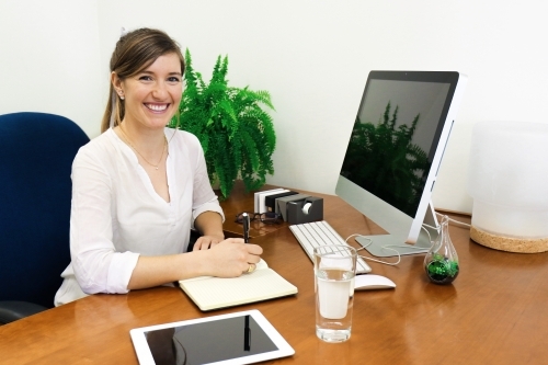 Portrait of young professional woman looking at camera from her office desk - Australian Stock Image