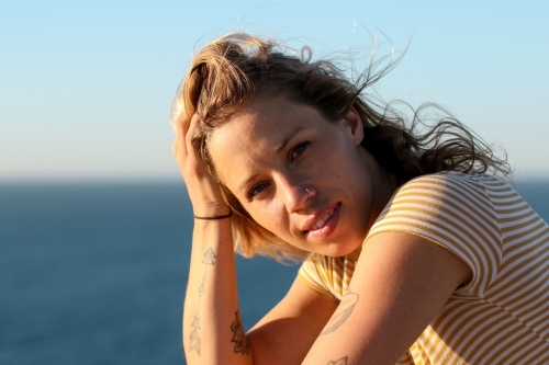Portrait of young woman in morning sunlight by the ocean - Australian Stock Image