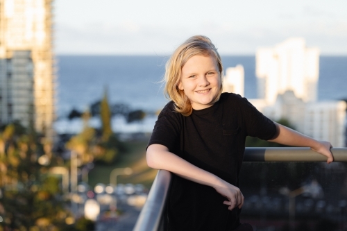 Pre-teen boy standing on balcony of high rise building on the Gold Coast with view - Australian Stock Image
