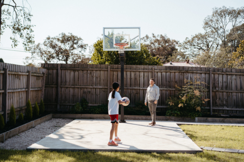 Pre-teen girl playing basketball with dad in their backyard - Australian Stock Image