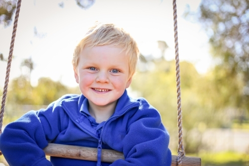 Preschool age child posing on rope ladder swing for kindergarten photos. Portrait of young boy. - Australian Stock Image