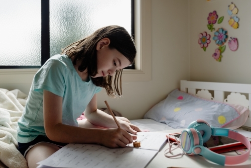 Primary school girl student at home using tablet computer for remote online learning covid-19 2020 - Australian Stock Image