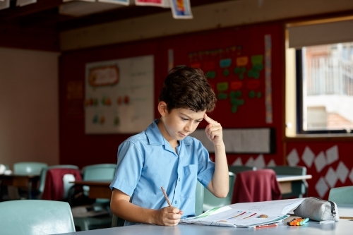 Primary school student in classroom working on homework - Australian Stock Image