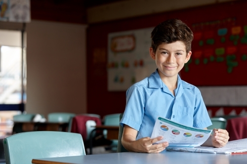 Primary school student in classroom working on homework - Australian Stock Image