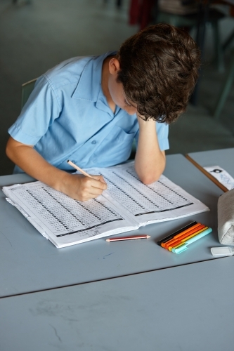 Primary school student in classroom working on homework - Australian Stock Image
