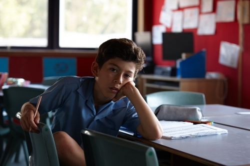 Primary school student in classroom working on homework - Australian Stock Image