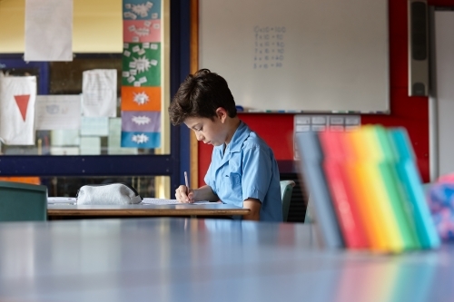 Primary school student in classroom working on homework - Australian Stock Image