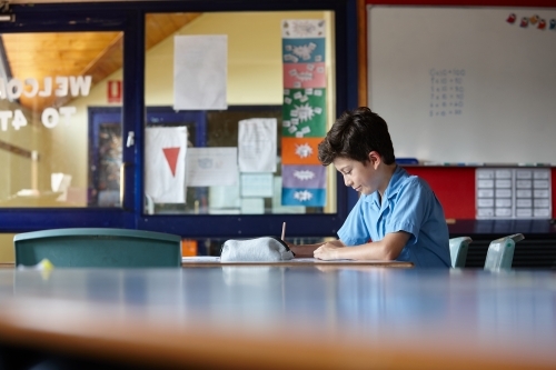 Primary school student in classroom working on homework - Australian Stock Image