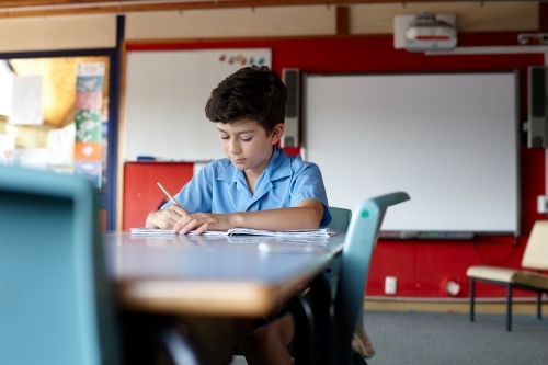 Primary school student in classroom working on homework - Australian Stock Image