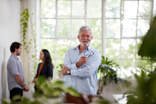 Professional businessman standing, thinking in an open plan office studio - Australian Stock Image