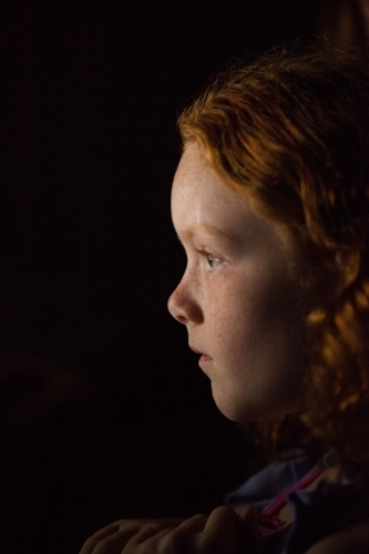 Profile of a young girl in low light - Australian Stock Image