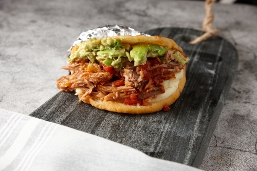 Pulled pork sandwich mashed avocado served on a marble cutting board - Australian Stock Image