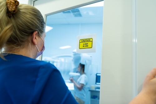 Radiography operator watching dental OPG X-ray being taken on young woman - Australian Stock Image