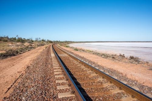 Railway track leading into the distance with salt lake next to it